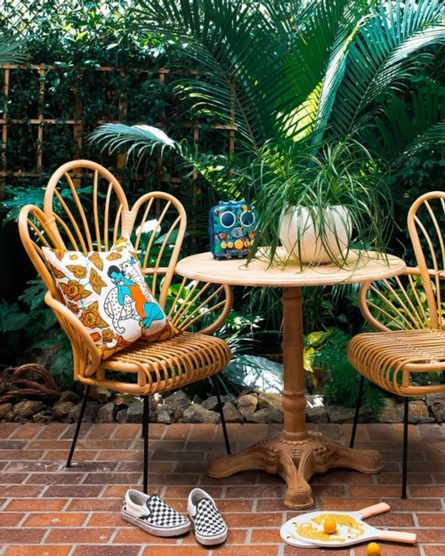 Outdoor setting with wicker chairs, table, and decorative items in a garden.